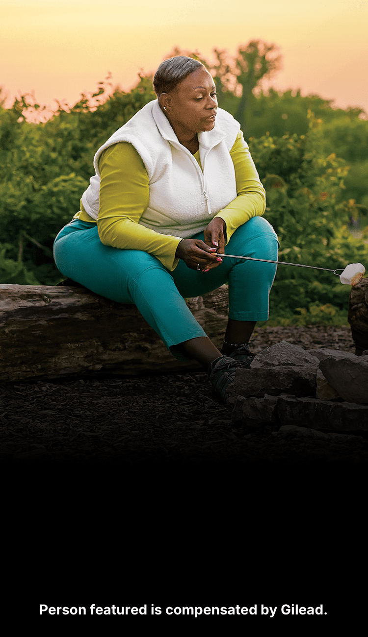 Angela, a woman with PBC, roasting marshmallows with her husband at sunset