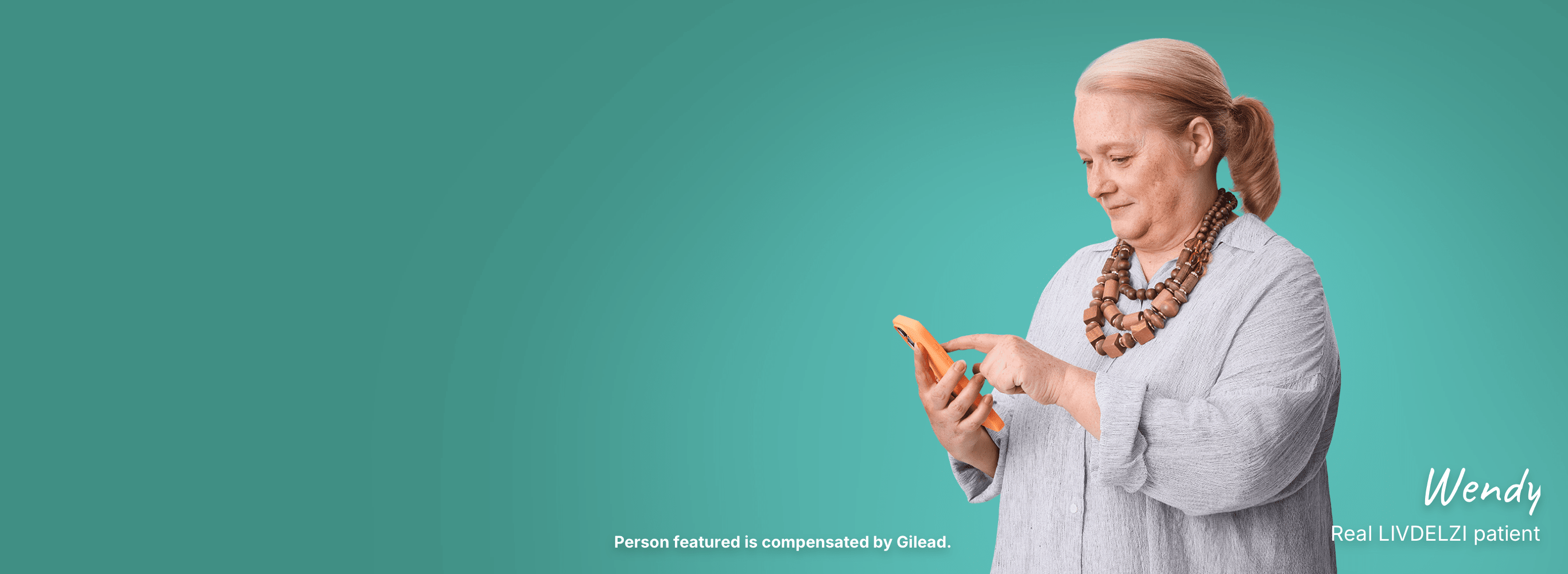 Wendy, a woman with PBC, reading her phone standing on a teal background